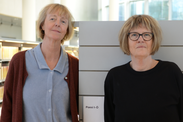 Bibliotekarierna Jeanette Malm och Elisabeth Skog står framför en bokhylla i ett bibliotek.