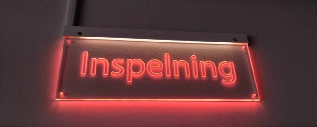 Fotografi på en lysande skylt där det står "Inspelning".  