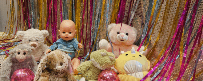 Nallar och dockor i olika färger mot en glittig bakgrund.