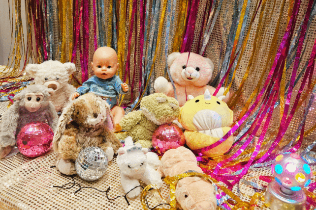 Nallar och dockor i olika färger mot en glittig bakgrund.