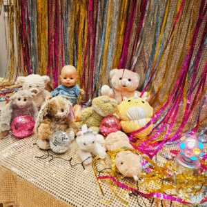 Nallar och dockor i olika färger mot en glittig bakgrund.