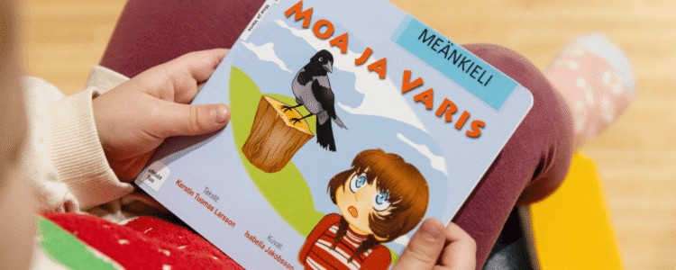 Barnbok med texten Moaja Varis och klisterklapp med Meänkieli.