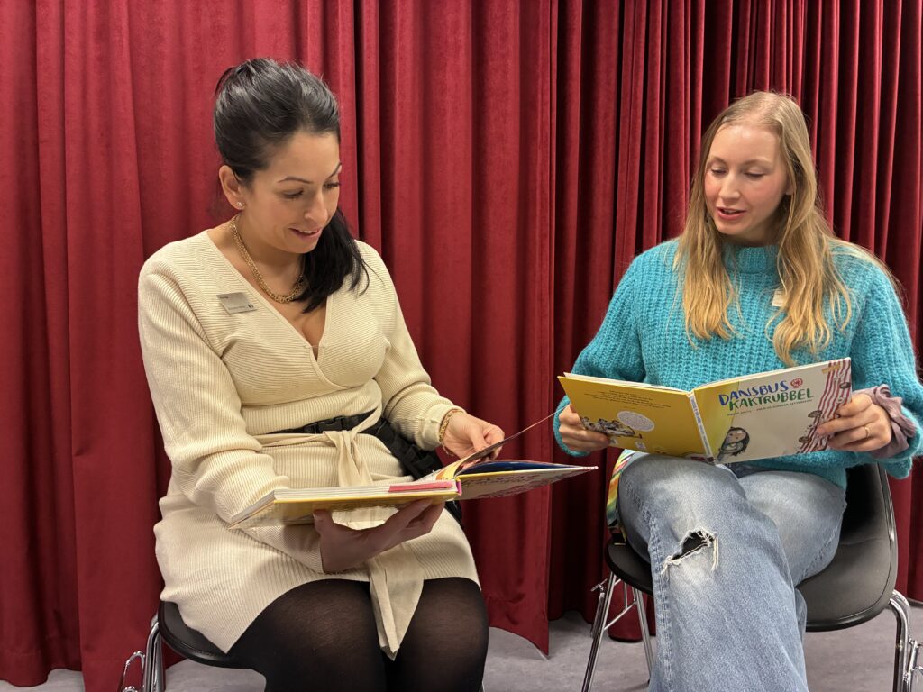 Två personer sitter och läser i boken Dansbus och kaktrubbel. 