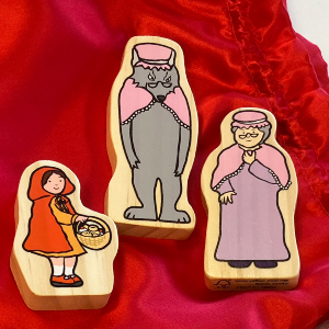 Fyra träfigurer föreställande karaktärerna från sagan om Rödluvan: en skogshuggare med yxa, Rödluvan med korg, den stora grå vargen och mormor. De ligger på ett rött silkestyg.