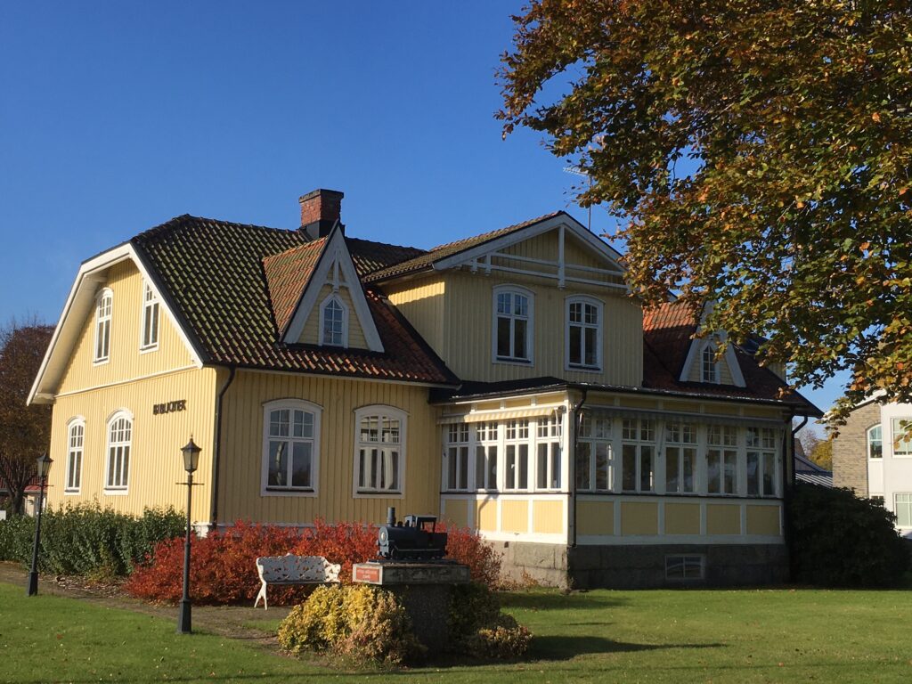 Fotografi på en gul gammeldags trävilla med veranda.