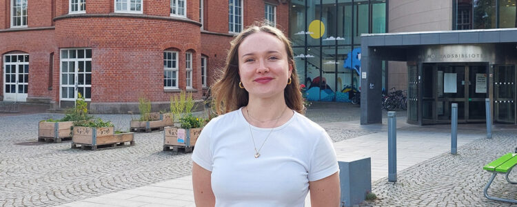Foto. Tova står utanför Malmö stadsbibliotek.