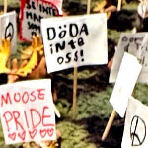 Miniatyrdiorama av en skog där små älgfigurer demonstrerar med handgjorda skyltar på tandpetare, bland annat "Låt skogen va!", "Moose pride" och "Döda inte oss!".